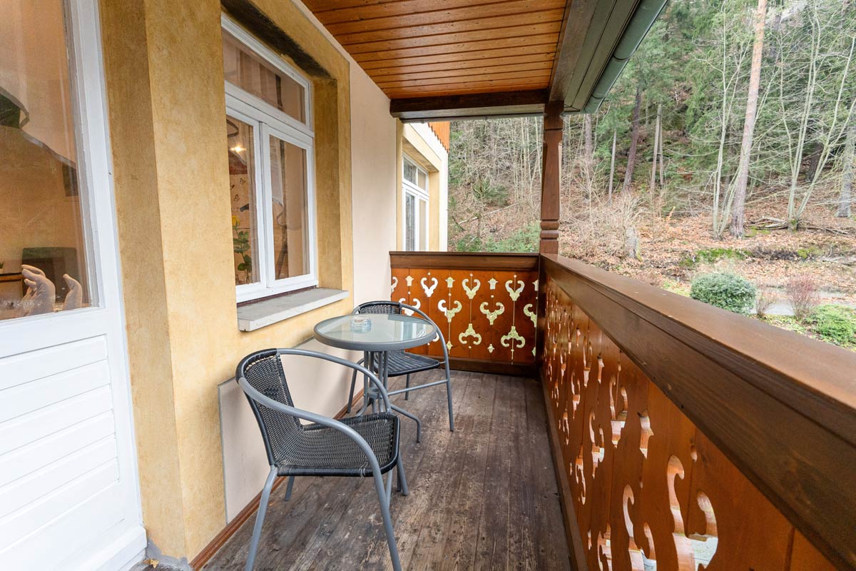 Der überdachte Holzbalkon mit Sitzmöglichkeiten, Tisch und Blick in den angrenzenden Wald.