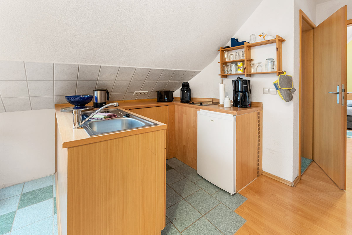 Blick in die Küchenzeile in Naturholzoptik der Ferienwohnung im Dachgeschoss mit schräger Wand.