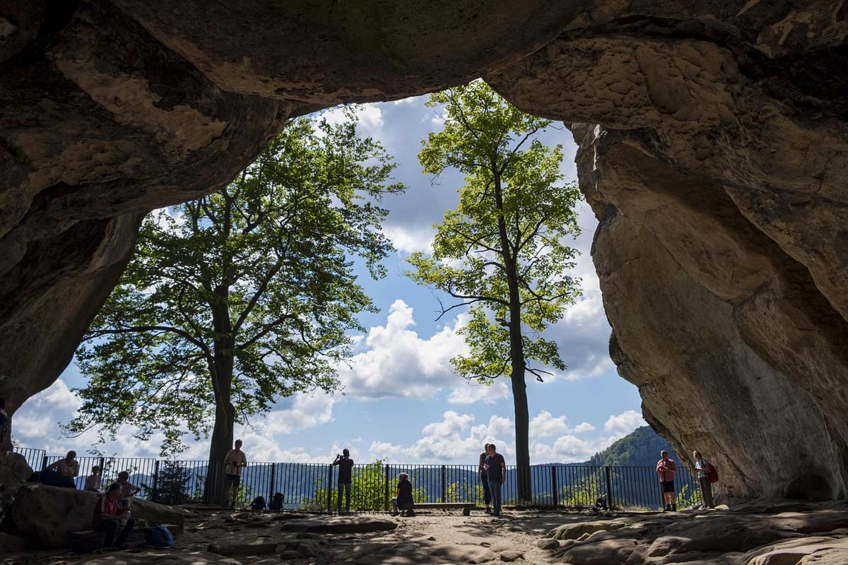 Blick durch den Kuhstall in der Sächsischen Schweiz Blick durch den Kuhstall in der Sächsischen Schweiz auf belaubte Bäume und einen blauen Himmel mit weißen Wolken
